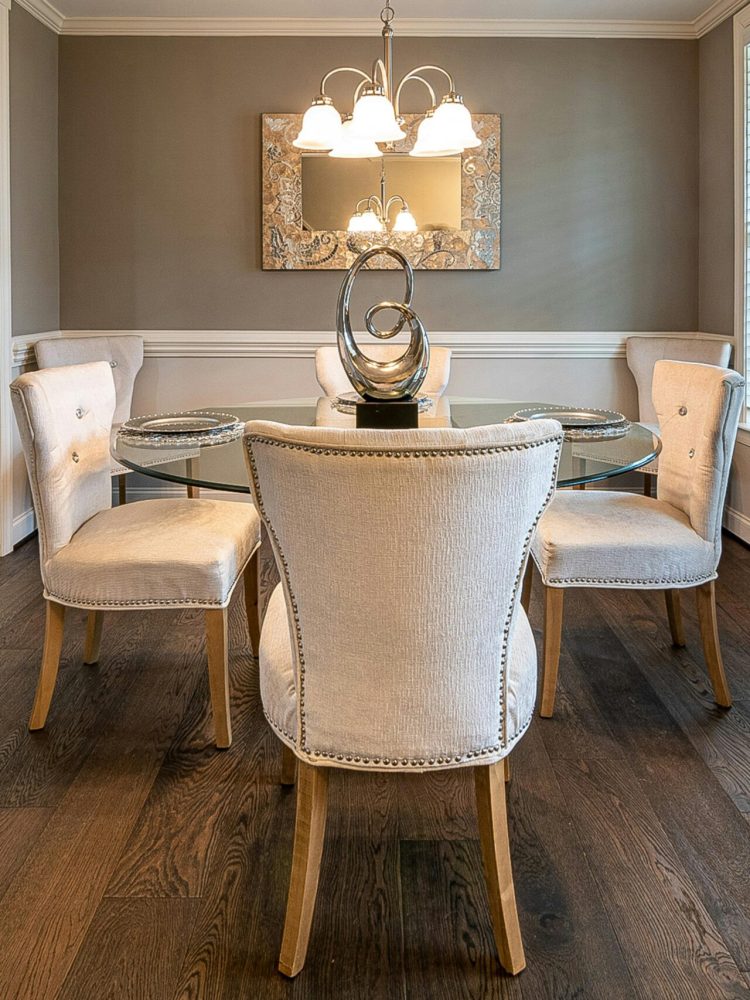 A sophisticated dining room with elegant chairs, a glass table, and tasteful decor.